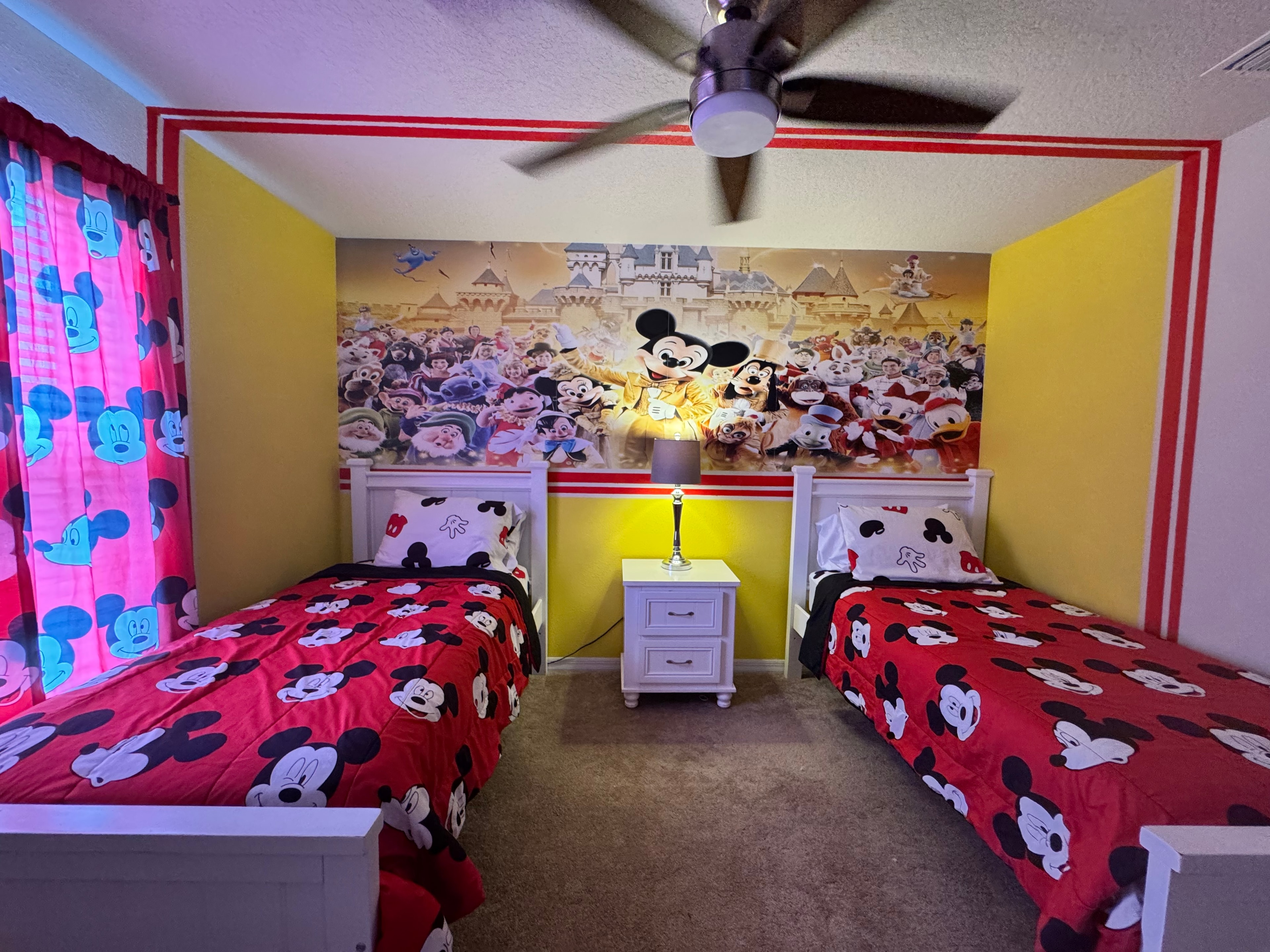 Mickey Mouse themed bedroom with twin beds and Disney mural